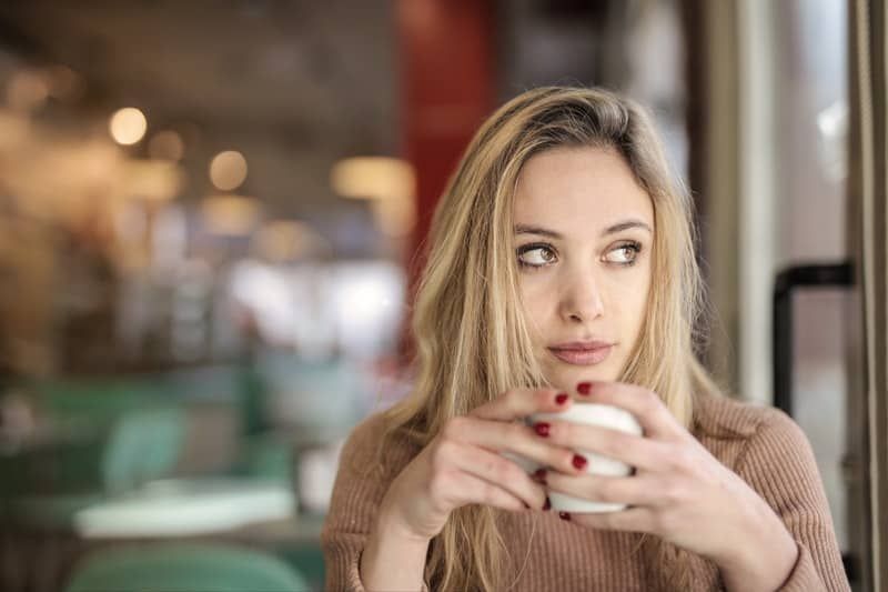 wanita termenung minum kopi di dalam kafe
