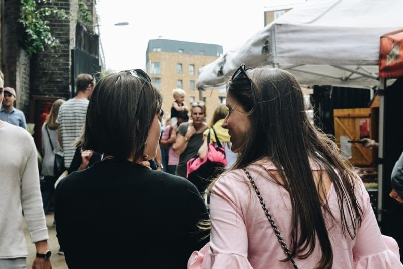 due donne che camminano vicino a bancarelle di cibo durante il giorno