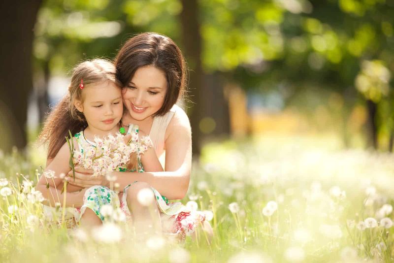 một người phụ nữ ngồi trên bãi cỏ với một đứa trẻ