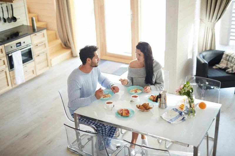 casal tomando café da manhã na mesa da cozinha e falando sério