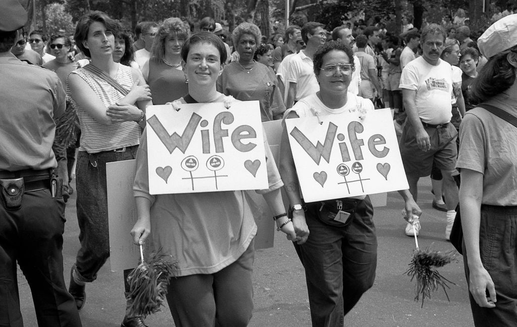 casal do mesmo sexo sorrindo, de mãos dadas na parada do orgulho gay nyc 1989