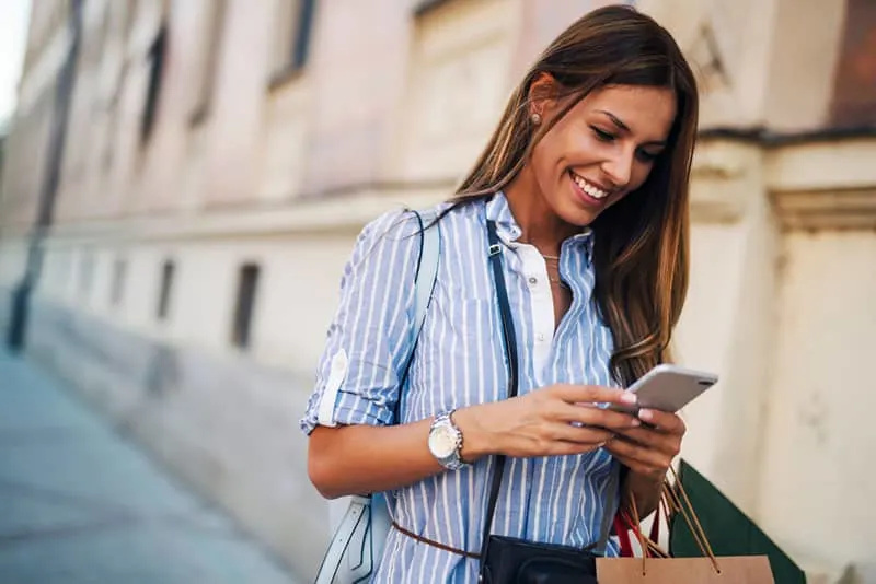 glückliche Frau, die auf das Telefon schaut