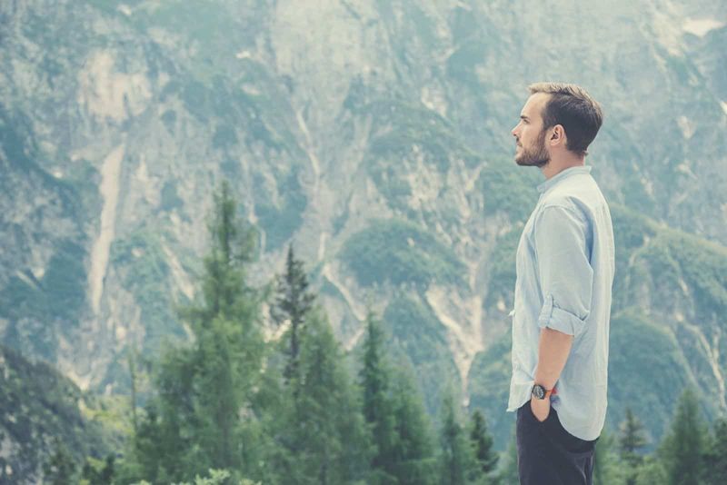 người đàn ông trẻ tuổi theo phong cách hipster du lịch trên núi nhìn ra thiên nhiên