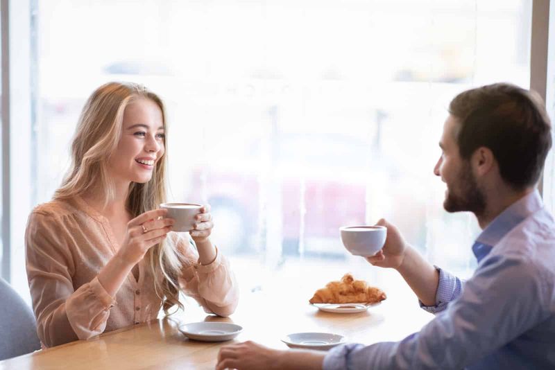 Lächelndes Liebespaar, das beim Kaffee sitzt und lacht