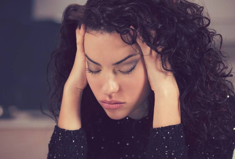 Porträt einer gestressten traurigen jungen Frau, die zu Hause sitzt