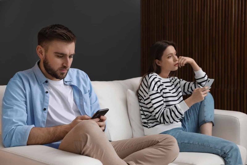 мужчина и женщина используют смартфоны, сидя на диване