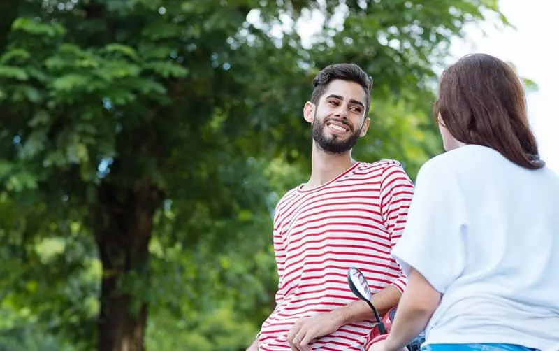 mladý pár flirtuje vonku'aperto vicino a un albero