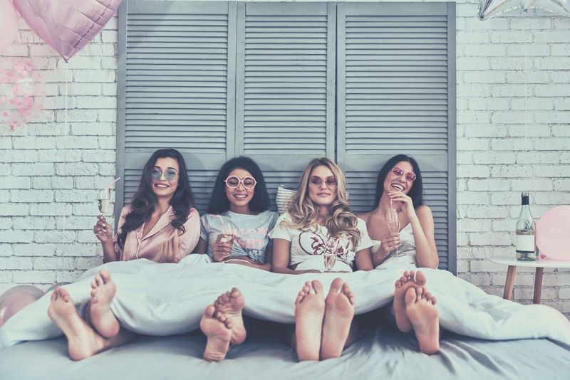 vier aantrekkelijke jonge vrouwen in hun nachtjaponnen die in bed zitten en cocktails drinken