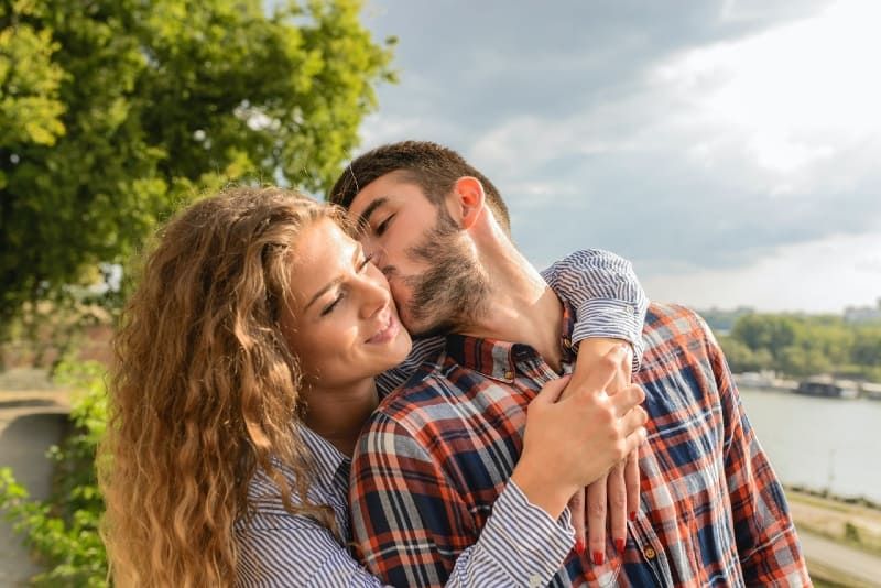 moški v karirani srajci poljublja žensko na prostem