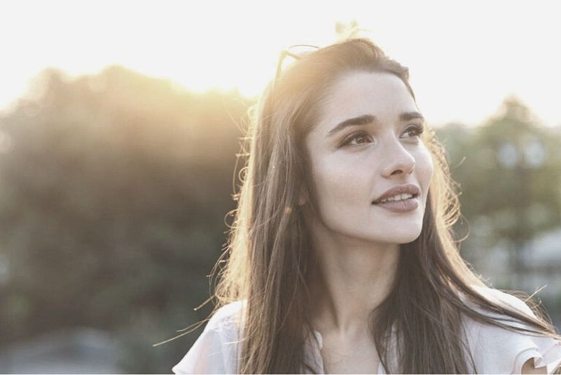 femeie inspirată privind cerul zâmbind cu ochelari pe cap