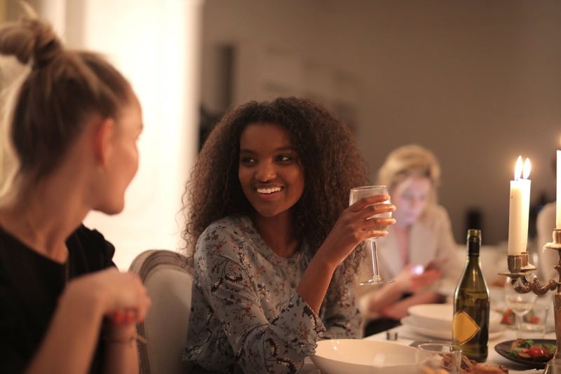 femeie ținând un pahar de vin în timp ce se uită la femeie