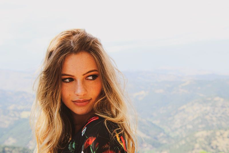 žena u crnom cvjetnom vrhu stoji na brdu