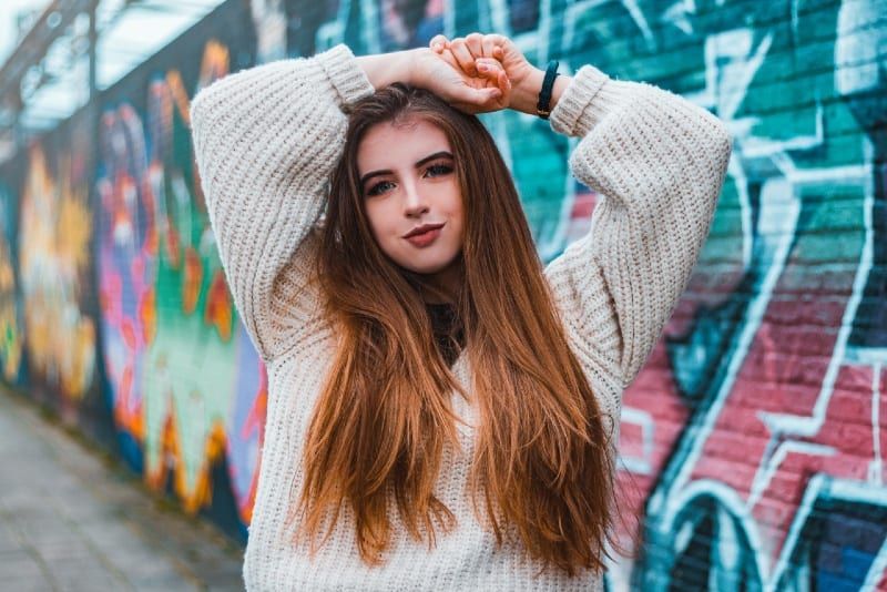 žena u džemperu koja stoji u blizini zida s grafitima