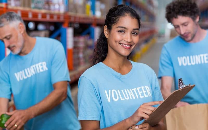 trei persoane sunt voluntare în cămașă albastră cu cuvântul voluntar