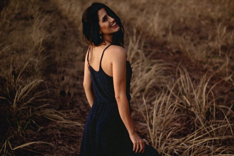 lächelnde Frau im Kleid, die auf dem Feld steht