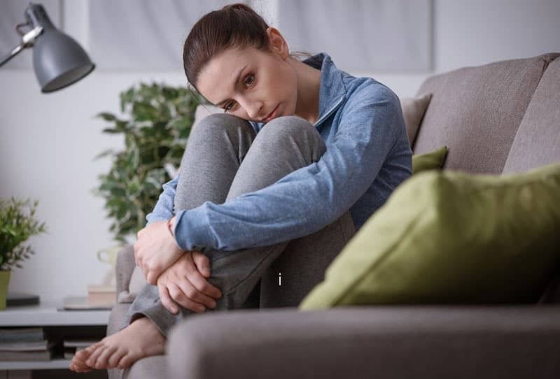vrouw met voeten weggestopt zittend op de bank in de woonkamer