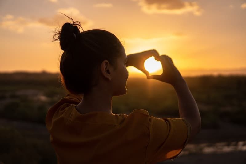 vrouw doet handtekenhart met de zon erin