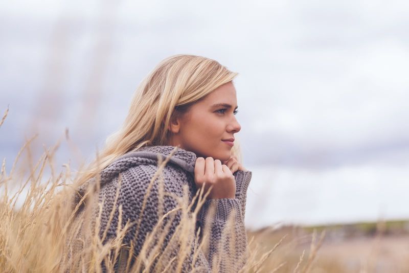 uma bela loira senta-se em um campo e pensa