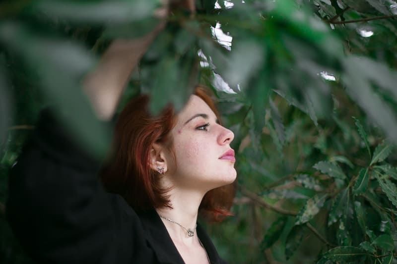 Frau, die unter grünem Baum steht