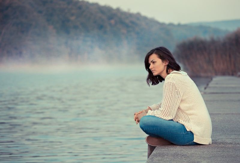 niña sentada junto al lago