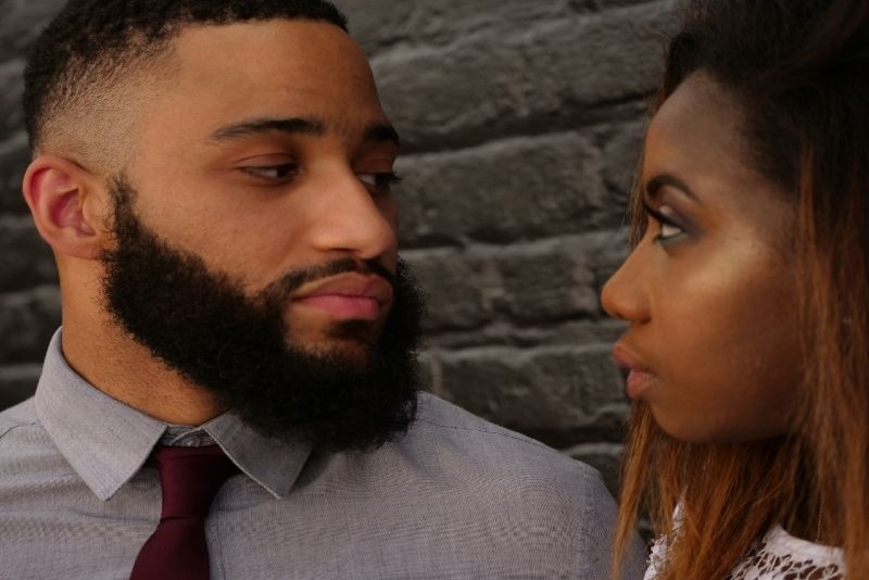 man en vrouw die oogcontact maken terwijl ze bij de muur staan