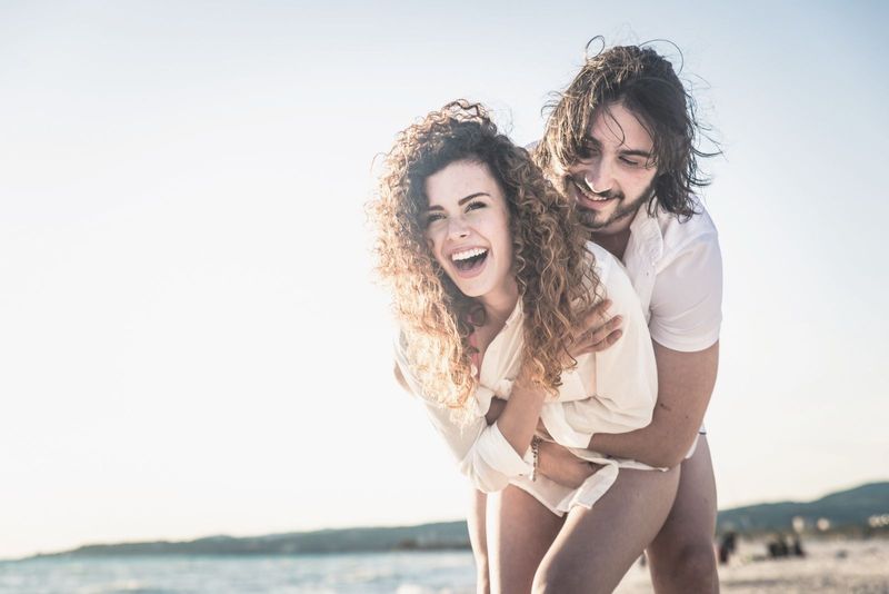 jonge gelukkige paar knuffelen en lachen op het strand