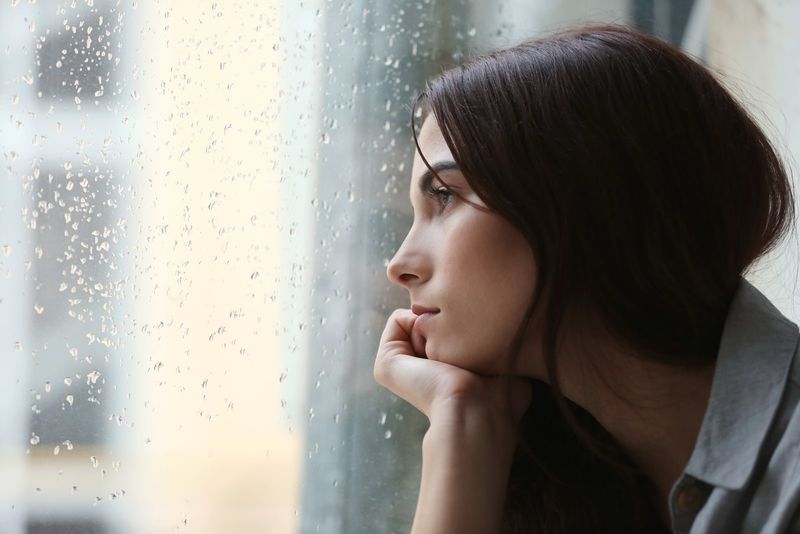 透过雨窗望去的悲伤女人