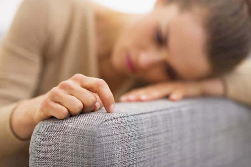 traurige frau, die im wohnzimmer liegt und denkt
