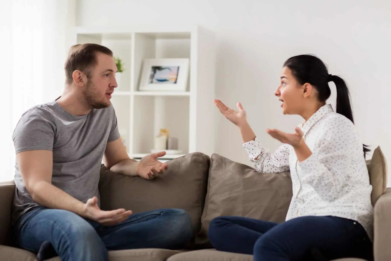   un home i una dona estan asseguts al sofà discutint