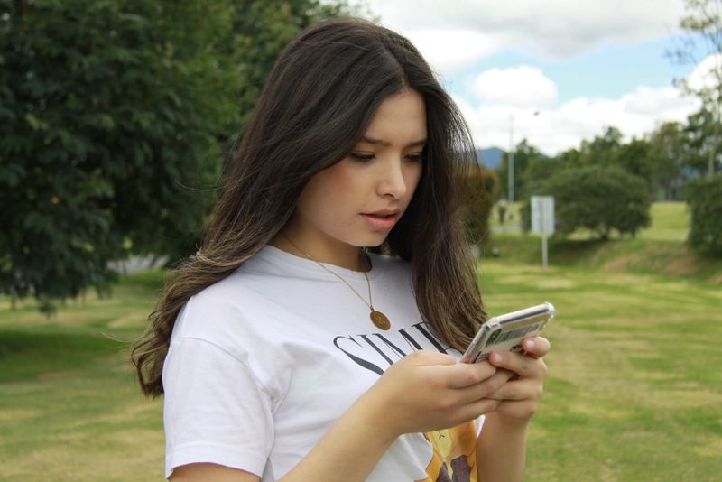 женщина разговаривает по телефону, стоя возле дерева