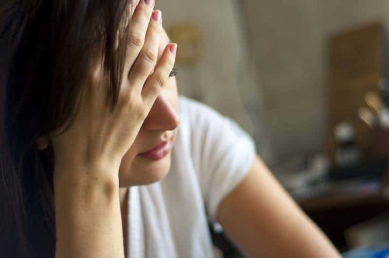 besorgte frau, die zu hause sitzt und ihren kopf hält