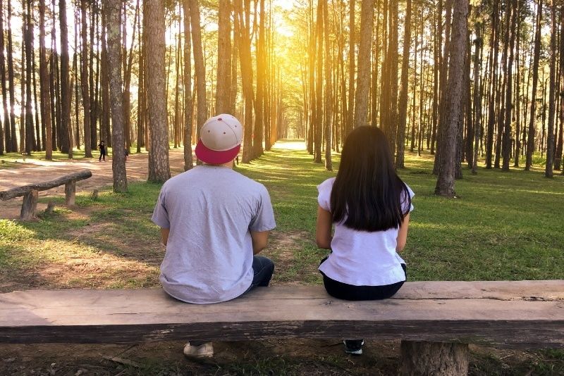 man en vrouw zittend op een bankje in het bos