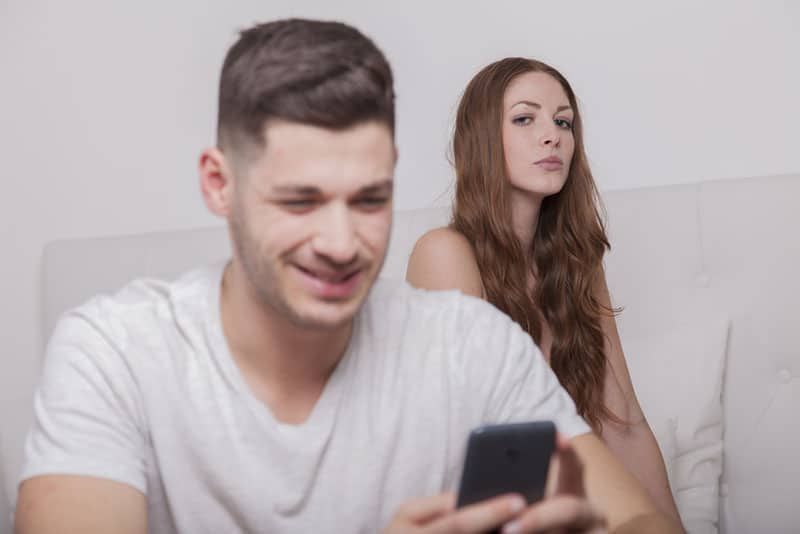 người phụ nữ nghiêm túc nhìn người đàn ông đang đánh máy