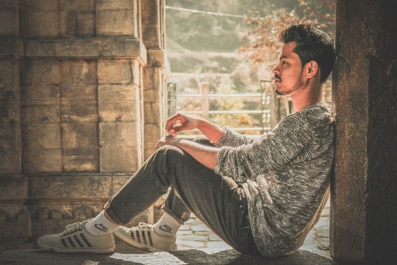 靠在墙上的灰色毛衣的男人