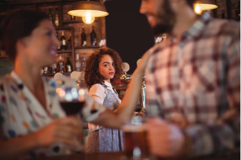 zazdrosna kobieta patrząca na mężczyznę flirtującego z inną kobietą w klubie