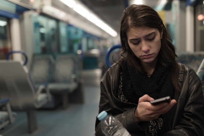 wanita yang duduk di kereta melihat teleponnya