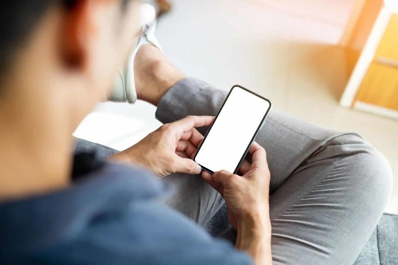   mężczyzna siedzi i pisze na telefonie