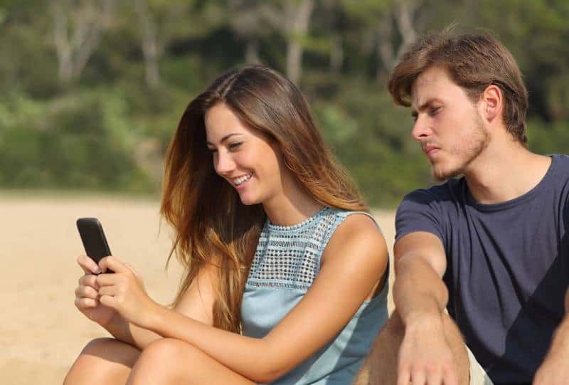 home gelós mirant el telèfon de la dona