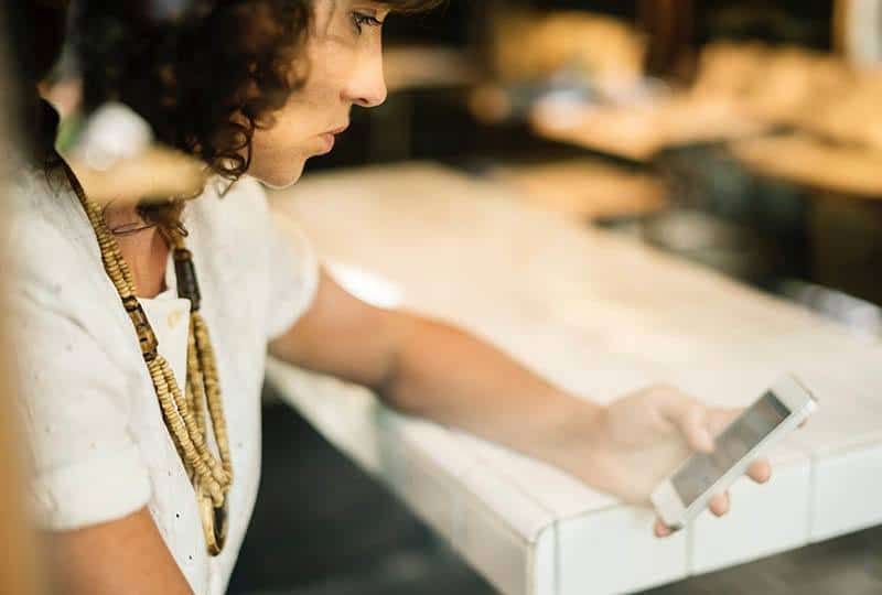 dona desesperada mirant el seu telèfon al cafè