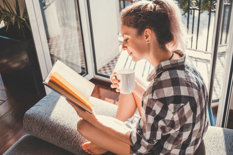 mulher tomando café e lendo livro