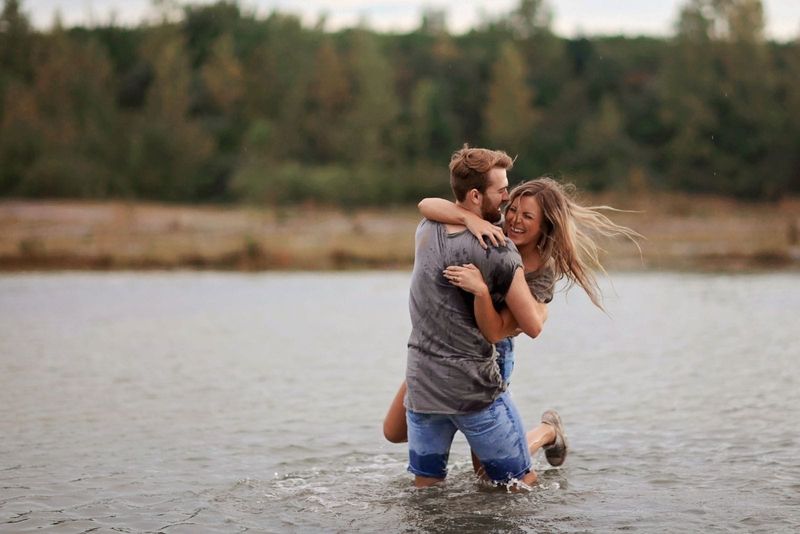 رجل يعانق ويلعب مع صديقته في الماء برفعها ضاحكا